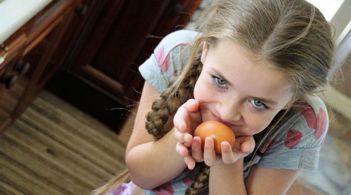 young girl holding a clementine in hands